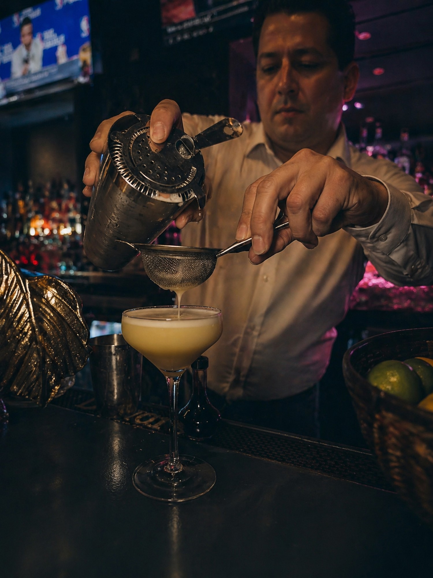 BARROOM bartender straining a freshly shaken cocktail